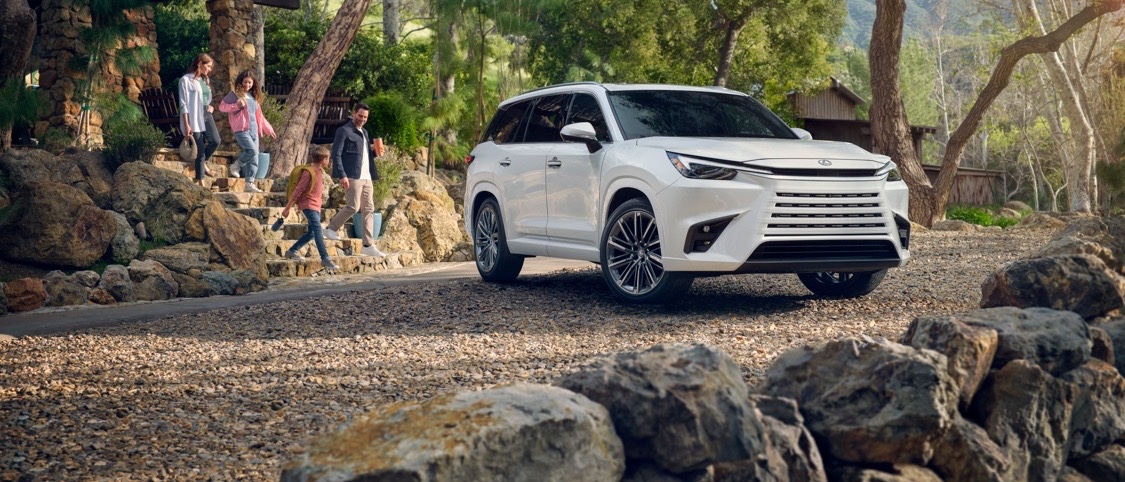 2026 Lexus TX 350 in white, parked on a stone path at golden hour with a family in view