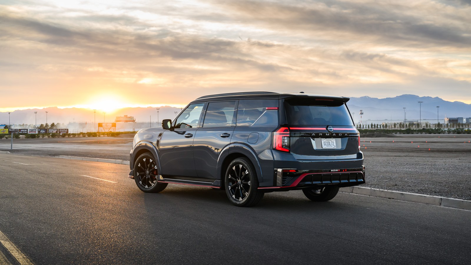 2026 Nissan Armada NISMO in pearl white with black contrast roof and red accents, rear three-quarter view at sunrise on a proving-ground tarmac