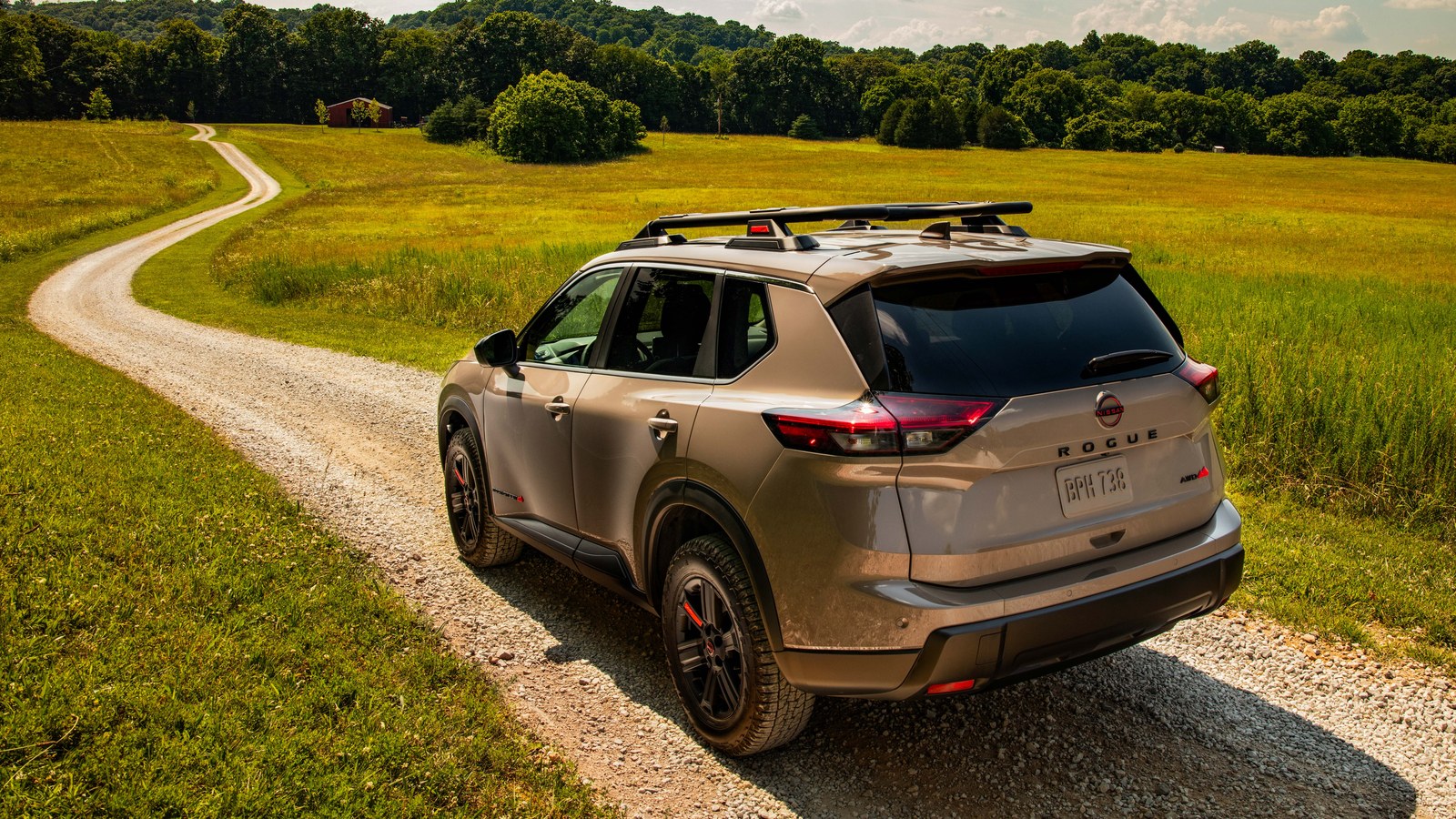 2026.5 Nissan Rogue Rock Creek edition in black, rear three-quarter view on a gravel road through an Iowa meadow